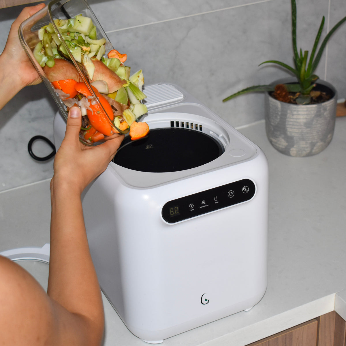 Woman adding vegetable scraps to the Green Experience Kitchen Composter 2.0 in a clean kitchen