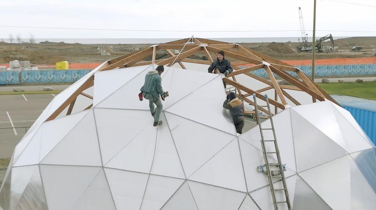 Team installing a geodesic dome greenhouse in a backyard
