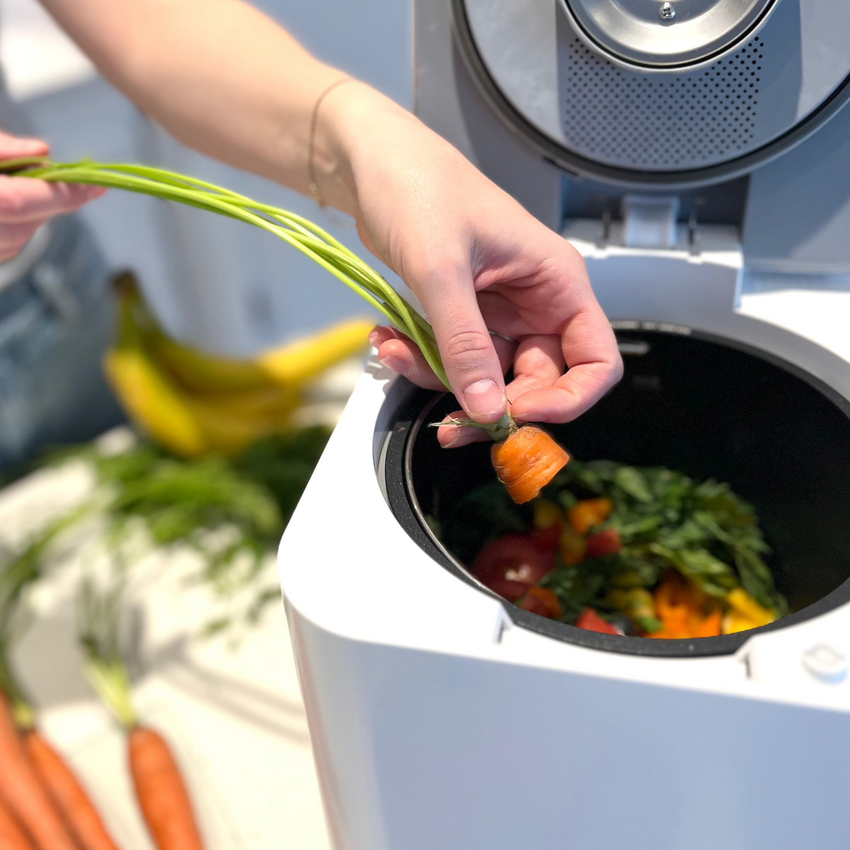 Woman adding food scraps to the Green Experience Kitchen Composter 1.0